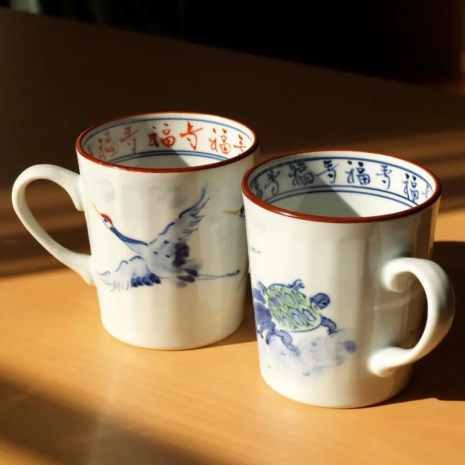Par de tazas de porcelana decoradas con grulla y tortuga, resistentes y con gran simbolismo.