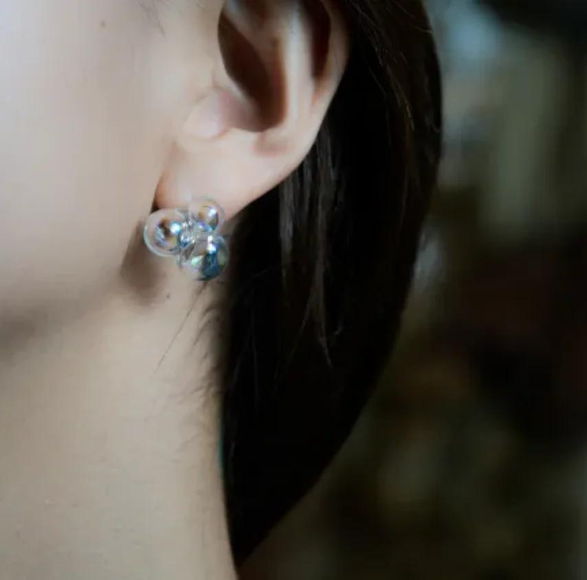 Par de aretes redondos de vidrio transparente, con acabado liso, disponibles en clip o perforados.