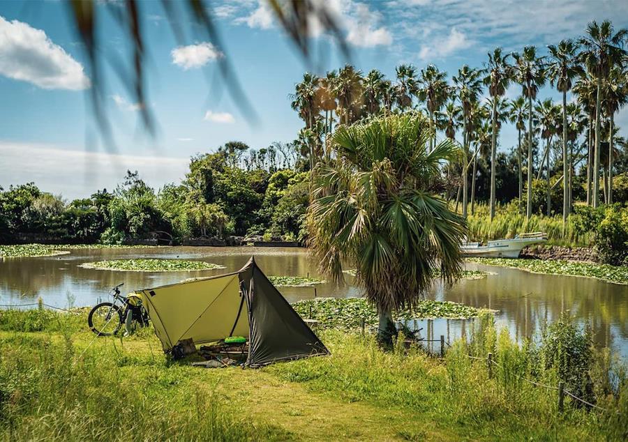 Tente Ogawa install&eacute;e en camping au bord d&rsquo;un lac avec v&eacute;lo, configuration l&eacute;g&egrave;re pour camping en solo ou itin&eacute;rant