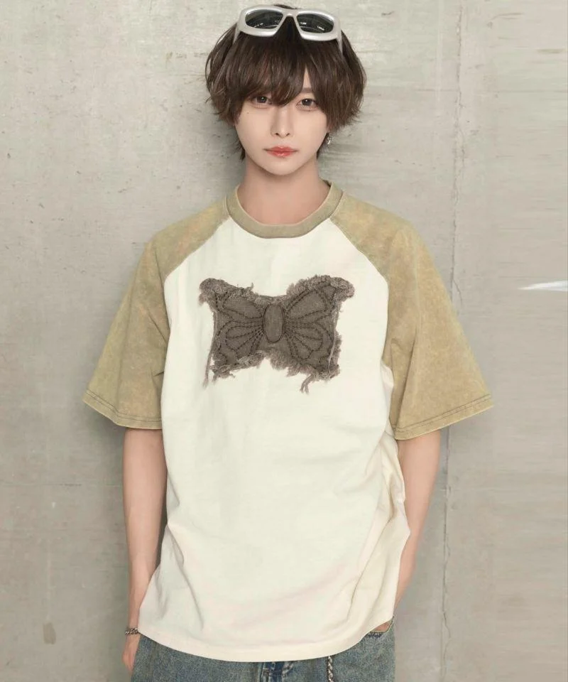 Modelo con camiseta raglán y mariposa de encaje, estilo relajado y urbano.