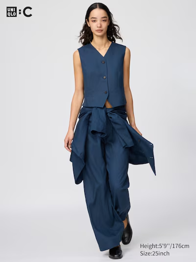 Femme portant une tenue minimaliste bleu foncé Uniqlo : gilet sans manches, pantalon large fluide et veste nouée à la taille.