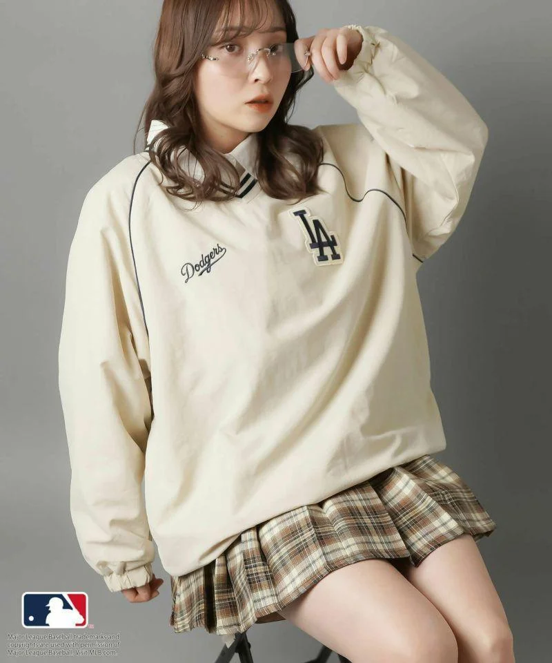 Chica con suéter de los Dodgers y falda escocesa, look inspirado en Blokecore vintage.