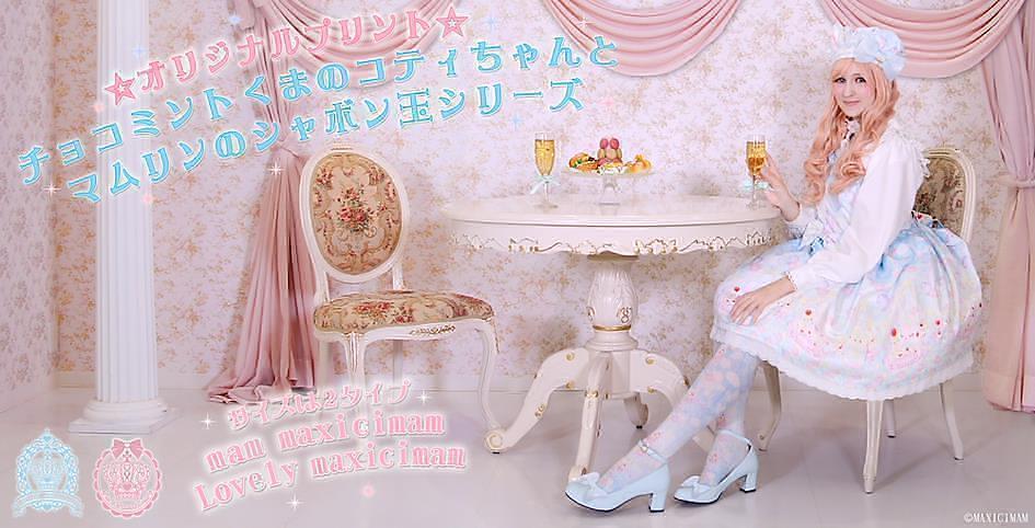 Una modelo sentada luciendo un vestido de la marca Maxicimam bebiendo junto a una mesa una bebida