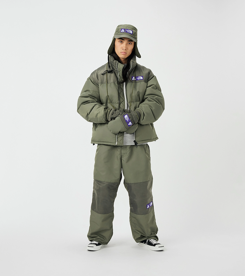 Homme portant une doudoune et un pantalon techniques kaki de THE NORTH FACE Purple Label, avec gants et chapka assortis, illustrant la fusion entre performance outdoor et esthétique urbaine du style gorpcore japonais.