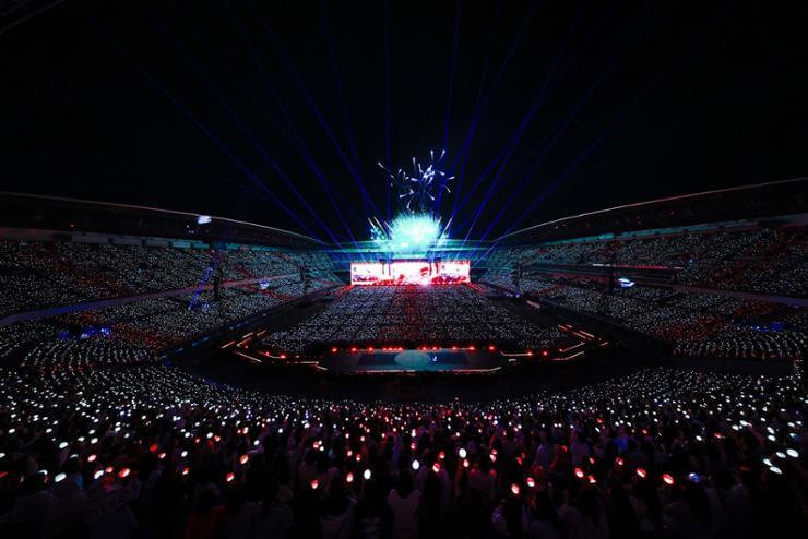 Concert du groupe SEVENTEEN au Japon, vue panoramique du stade rempli de fans brandissant leurs lightsticks synchronis&eacute;s pendant la tourn&eacute;e.