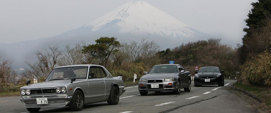 Japanese sports cars parked on a scenic mountain road.