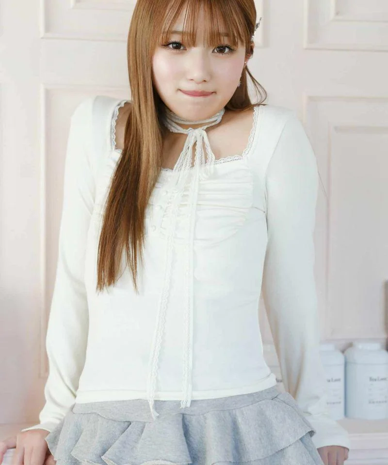 Chica con top blanco y falda gris estilo balletcore en interior de estética romántica.