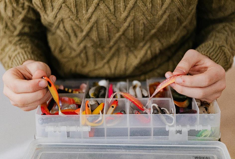 A person holding a plastic container with fishing baits